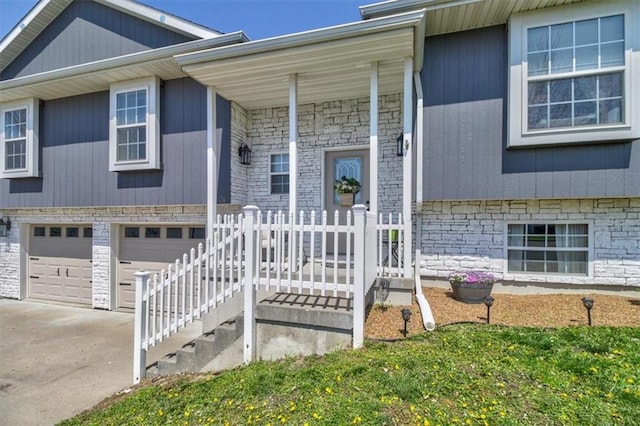 view of front of house with concrete driveway, a porch, stone siding, and an attached garage