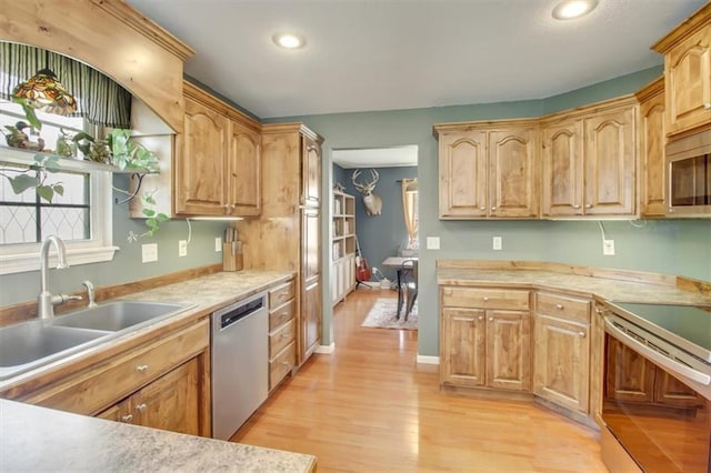 kitchen with a sink, light countertops, light wood finished floors, recessed lighting, and stainless steel appliances
