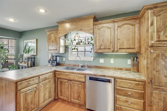 kitchen featuring stainless steel dishwasher, a peninsula, light wood-type flooring, light countertops, and a sink