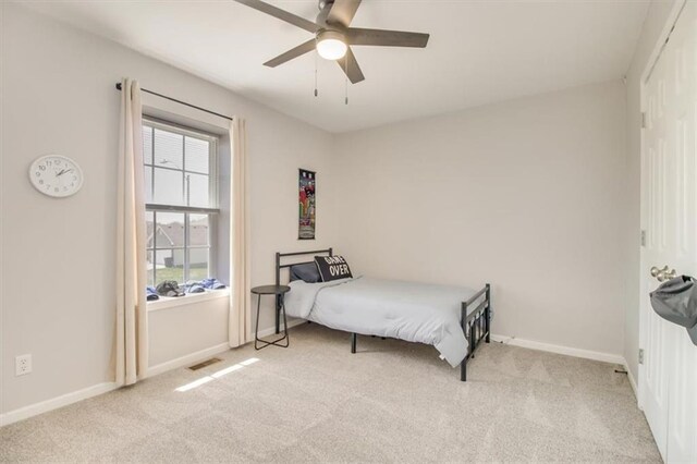 bedroom featuring visible vents, light colored carpet, baseboards, and a ceiling fan