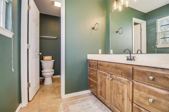bathroom with toilet, tile patterned floors, baseboards, and vanity
