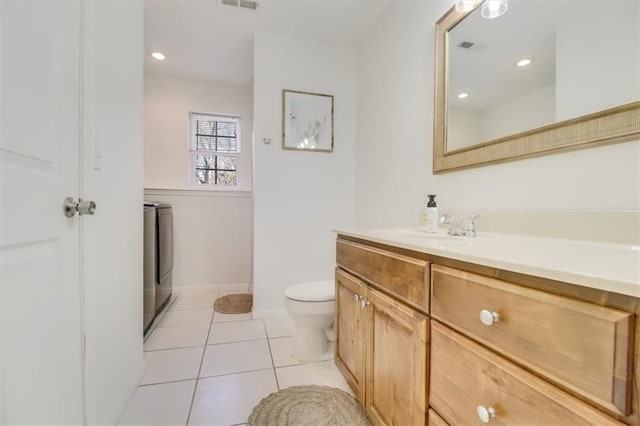 bathroom featuring vanity, visible vents, toilet, tile patterned floors, and washing machine and dryer