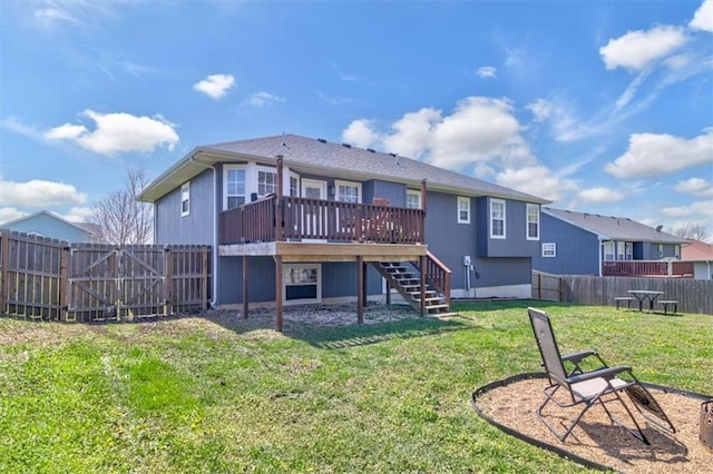 rear view of house with stairway, a fenced backyard, a yard, a deck, and a gate