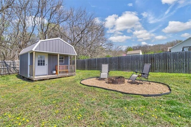 view of yard featuring a shed, a fire pit, a fenced backyard, and an outdoor structure