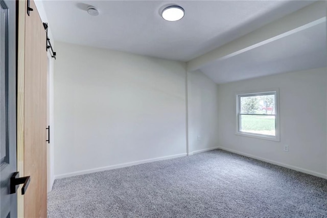spare room featuring baseboards, carpet flooring, a barn door, and lofted ceiling with beams