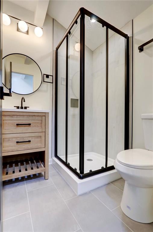 full bathroom featuring a shower stall, vanity, tile patterned flooring, and toilet