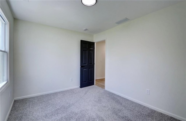 empty room with baseboards, visible vents, and carpet floors