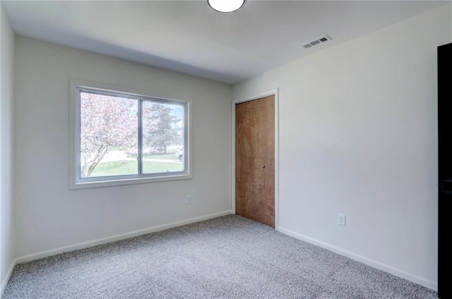 spare room with visible vents, baseboards, and carpet flooring