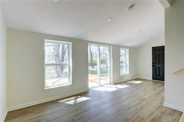 unfurnished living room with baseboards, wood finished floors, and lofted ceiling