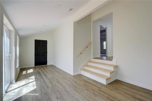 entryway featuring baseboards, vaulted ceiling, wood finished floors, and stairs