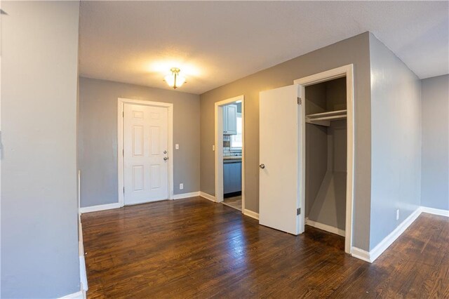 9904 E 60th Ter, Raytown, MO 64133 - unfurnished bedroom with a closet, baseboards, and dark wood finished floors