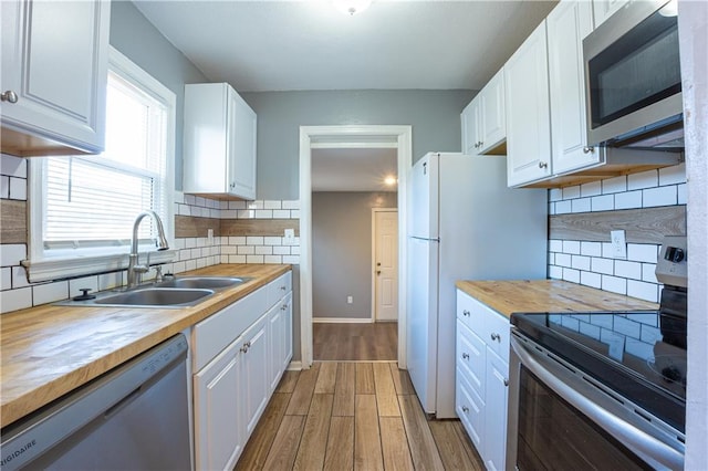 9904 E 60th Ter, Raytown, MO 64133 - kitchen featuring butcher block countertops, light wood-style flooring, white cabinets, stainless steel appliances, and a sink
