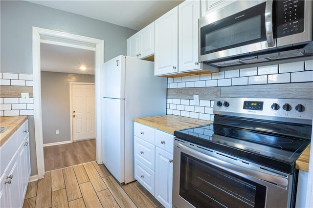 9904 E 60th Ter, Raytown, MO 64133 - kitchen featuring light wood-type flooring, wood counters, white cabinetry, decorative backsplash, and stainless steel appliances