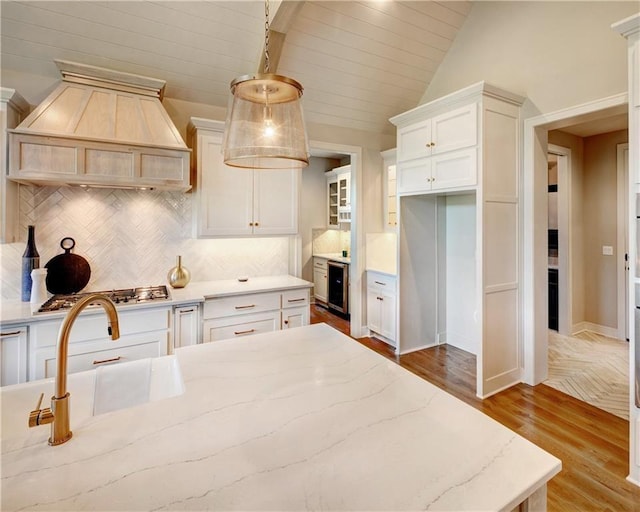 16046 S Twilight Ln, Olathe, KS 66062 - kitchen featuring wood finished floors, premium range hood, tasteful backsplash, white cabinetry, and light stone counters