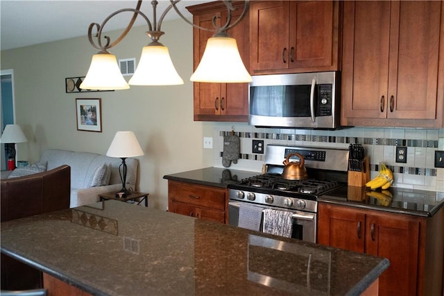 4413 E 107th St, Kansas City, MO 64137 - kitchen featuring stainless steel appliances, tasteful backsplash, open floor plan, dark stone countertops, and brown cabinetry