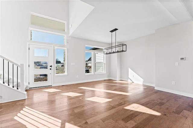 entryway featuring a chandelier, stairway, baseboards, and wood finished floors