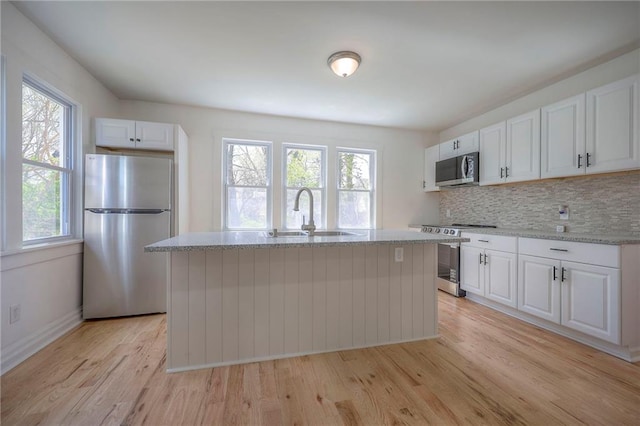 1607 E 37th St, Kansas City, MO 64109 - kitchen featuring stainless steel appliances, a sink, white cabinetry, and light wood finished floors