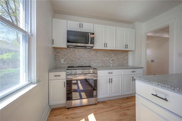 1607 E 37th St, Kansas City, MO 64109 - kitchen featuring appliances with stainless steel finishes, tasteful backsplash, light wood finished floors, and white cabinets