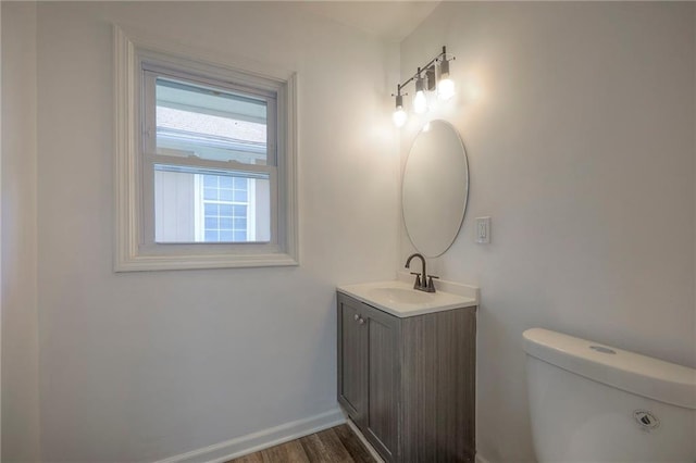 1607 E 37th St, Kansas City, MO 64109 - half bathroom featuring vanity, toilet, wood finished floors, and baseboards