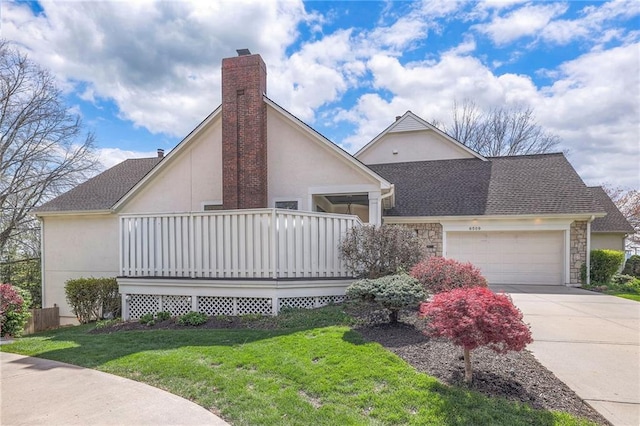 view of front of house with a front yard, an attached garage, a chimney, stucco siding, and driveway