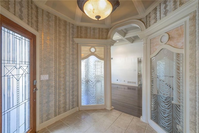 foyer entrance featuring crown molding, ornate columns, light tile patterned flooring, wallpapered walls, and baseboards