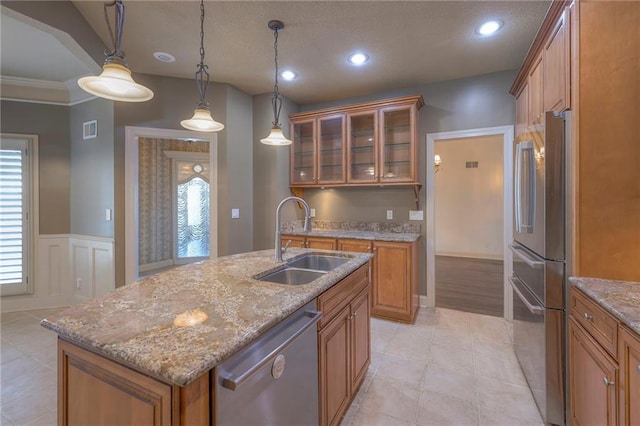 kitchen with visible vents, glass insert cabinets, a sink, brown cabinetry, and stainless steel appliances