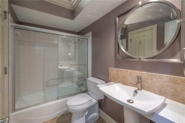 full bathroom with combined bath / shower with glass door, ornamental molding, a sink, and toilet