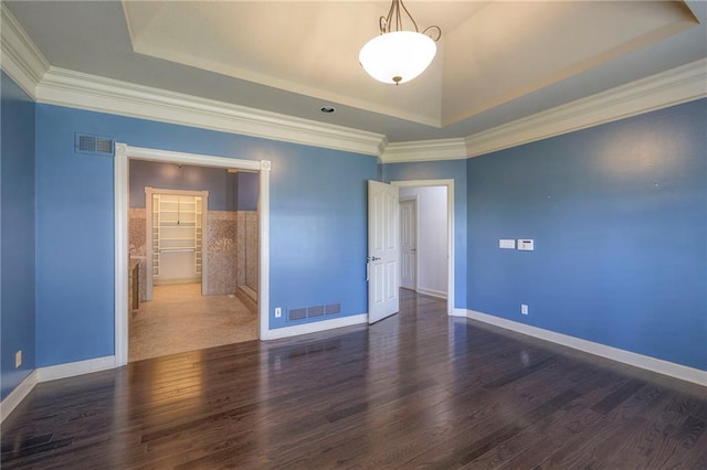 spare room featuring visible vents, wood finished floors, and a raised ceiling