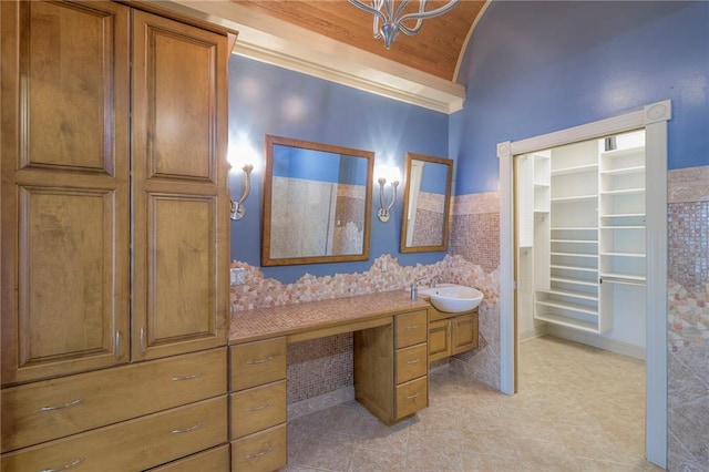 full bathroom featuring tile patterned flooring, vanity, vaulted ceiling, and a walk in closet