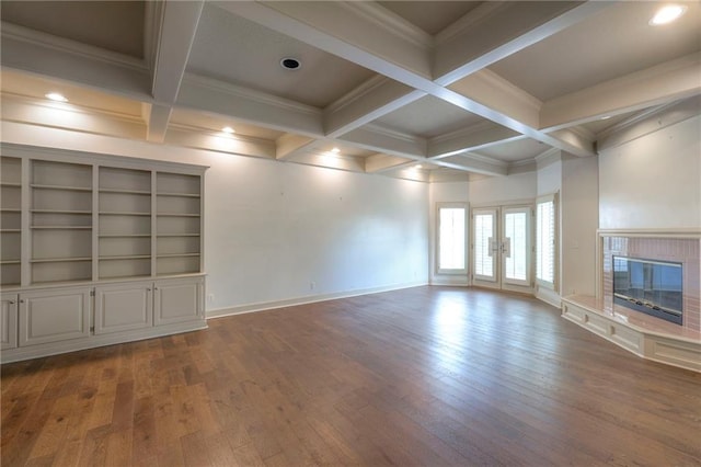 unfurnished living room featuring ornamental molding, wood-type flooring, a glass covered fireplace, and beamed ceiling