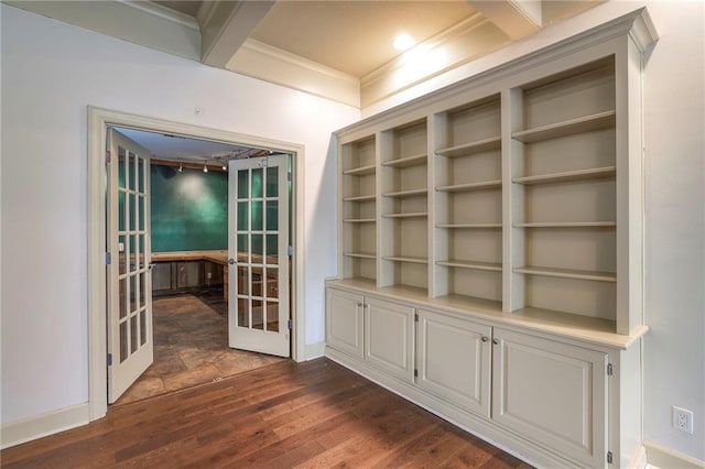 empty room featuring dark wood-type flooring, baseboards, ornamental molding, and french doors