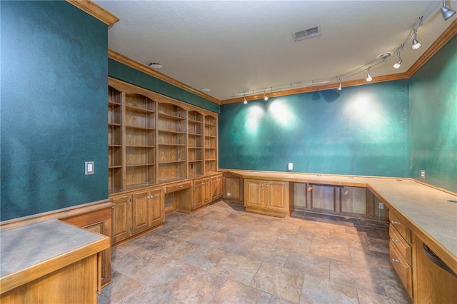 unfurnished office with crown molding, rail lighting, stone finish floor, visible vents, and built in study area
