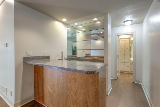 bar with a sink, baseboards, wet bar, and wood finished floors
