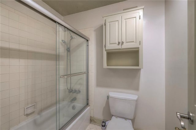 bathroom with toilet, shower / bath combination with glass door, and baseboards