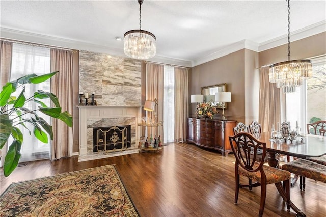 dining space featuring crown molding, a chandelier, wood finished floors, and a high end fireplace