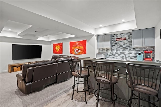 4513 NE Parks Summit Ter, Lees Summit, MO 64064 - kitchen with a raised ceiling, tasteful backsplash, gray cabinetry, and a breakfast bar