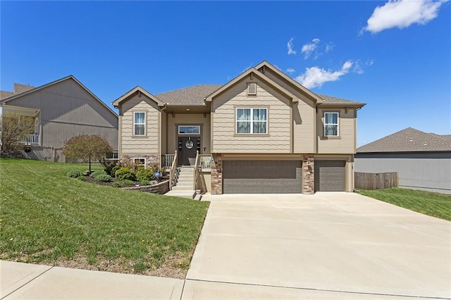 raised ranch featuring an attached garage, stone siding, a front lawn, and concrete driveway