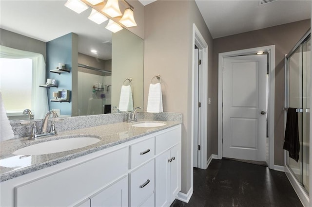 bathroom with a shower stall, double vanity, a sink, and baseboards