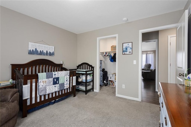 bedroom featuring light carpet, a closet, baseboards, and a spacious closet