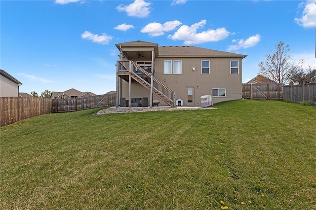 rear view of house with a yard, ceiling fan, a fenced backyard, and stairway