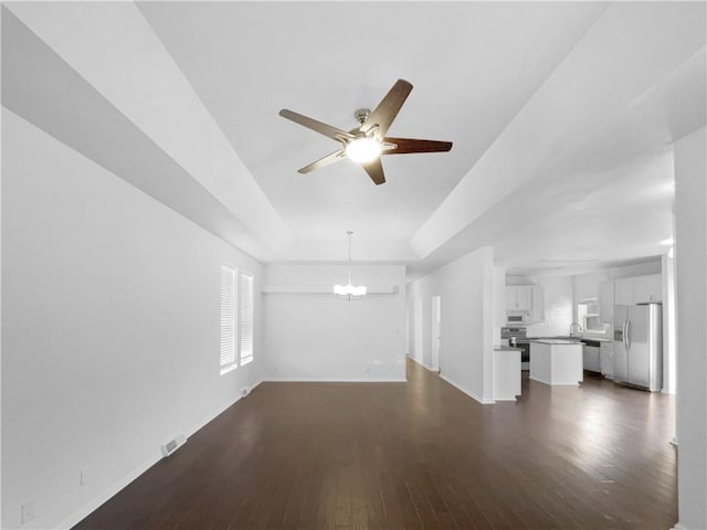 12207 N Pomona Ave, Kansas City, MO 64163 - unfurnished living room with a tray ceiling, dark wood-style flooring, and baseboards