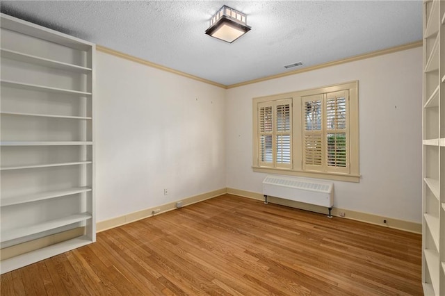 6721 Santa Fe Dr, Overland Park, KS 66204 - unfurnished room with ornamental molding, radiator, wood finished floors, and a textured ceiling