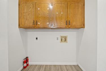 11930 Charlotte St, Kansas City, MO 64146 - laundry room with washer hookup, hookup for an electric dryer, cabinet space, and light wood finished floors