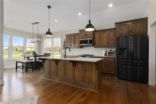 6604 NW 107th Ct, Kansas City, MO 64154 - kitchen with black fridge, stainless steel microwave, a sink, light countertops, and dark wood-style flooring