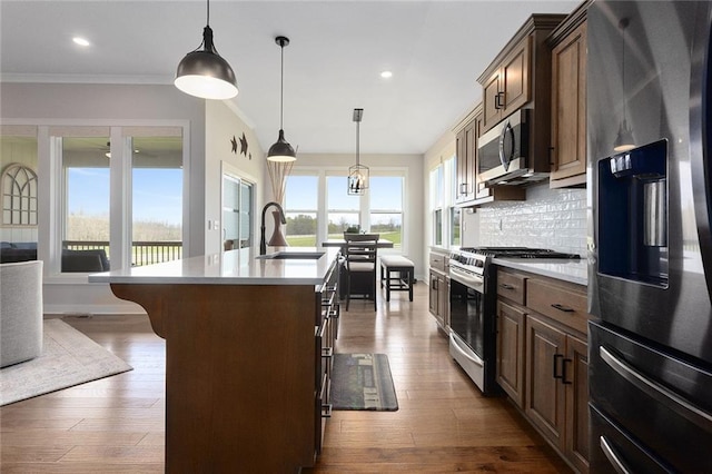 6604 NW 107th Ct, Kansas City, MO 64154 - kitchen featuring an island with sink, light countertops, backsplash, appliances with stainless steel finishes, and a sink