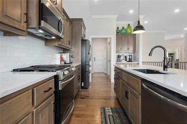 6604 NW 107th Ct, Kansas City, MO 64154 - kitchen with crown molding, dark wood finished floors, a sink, hanging light fixtures, and stainless steel appliances