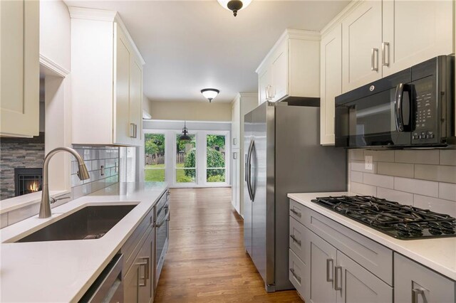 3600 W 48th St, Roeland Park, KS 66205 - kitchen with black appliances, a sink, light wood finished floors, light countertops, and tasteful backsplash