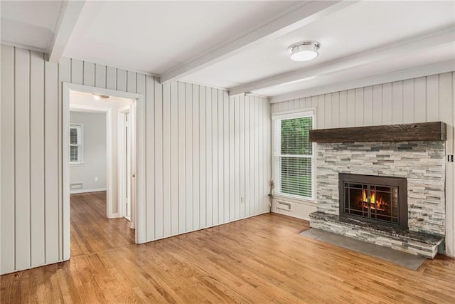 3600 W 48th St, Roeland Park, KS 66205 - unfurnished living room featuring beamed ceiling, light wood-style floors, a stone fireplace, and wooden walls