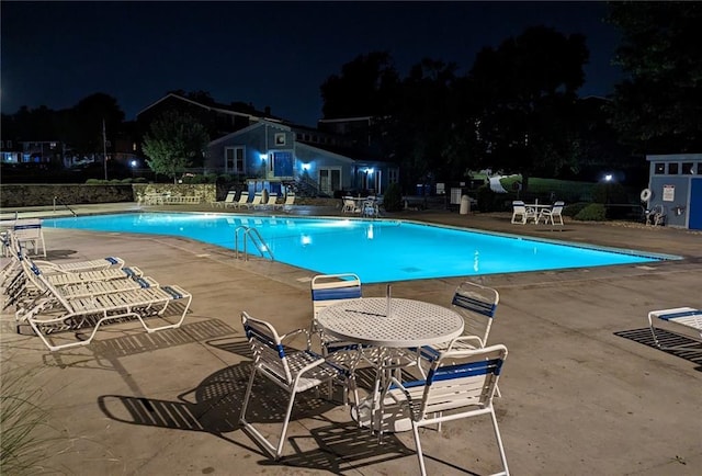 pool at twilight featuring a patio area and a community pool