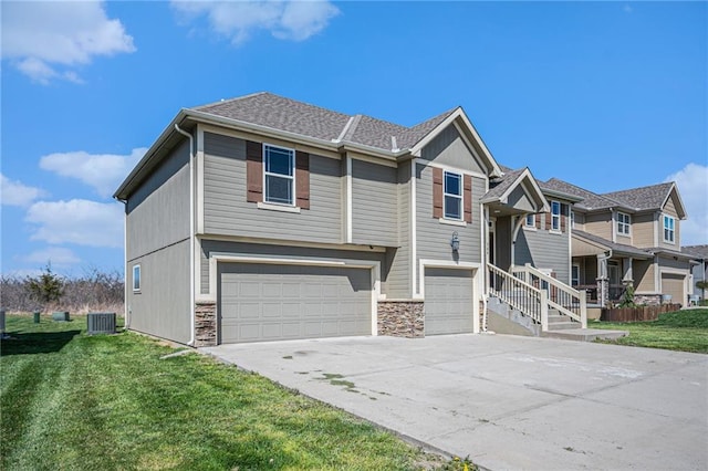 view of front of house featuring central air condition unit, a front yard, stone siding, an attached garage, and driveway